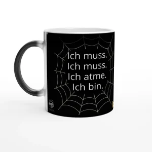 Schwarze Tasse mit einem Spinnennetz-Muster. Auf der Tasse steht: 'Ich muss. Ich muss. Ich atme. Ich bin.'
